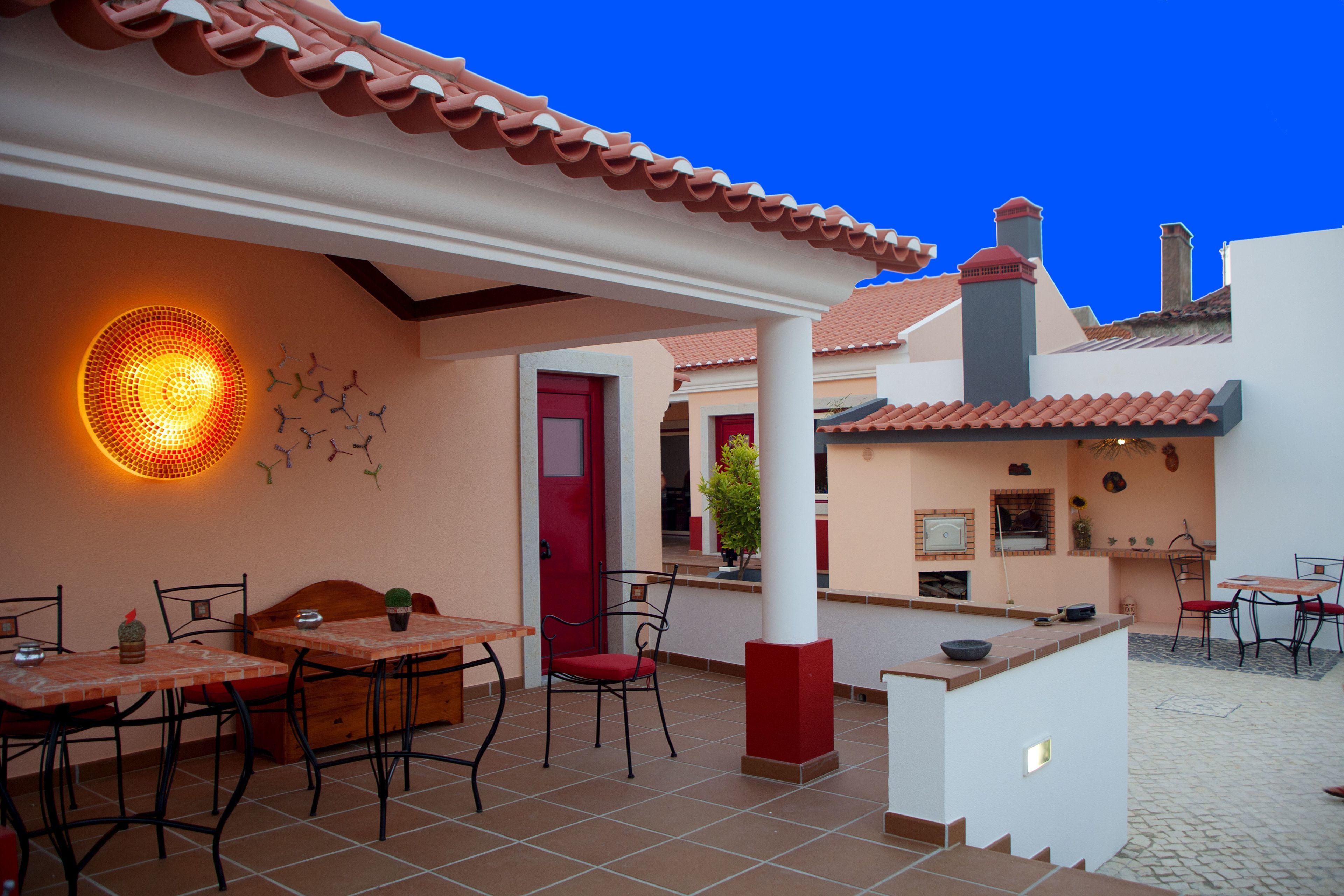 Un patio al aire libre con suelo de baldosas, una mesa de madera y sillas.