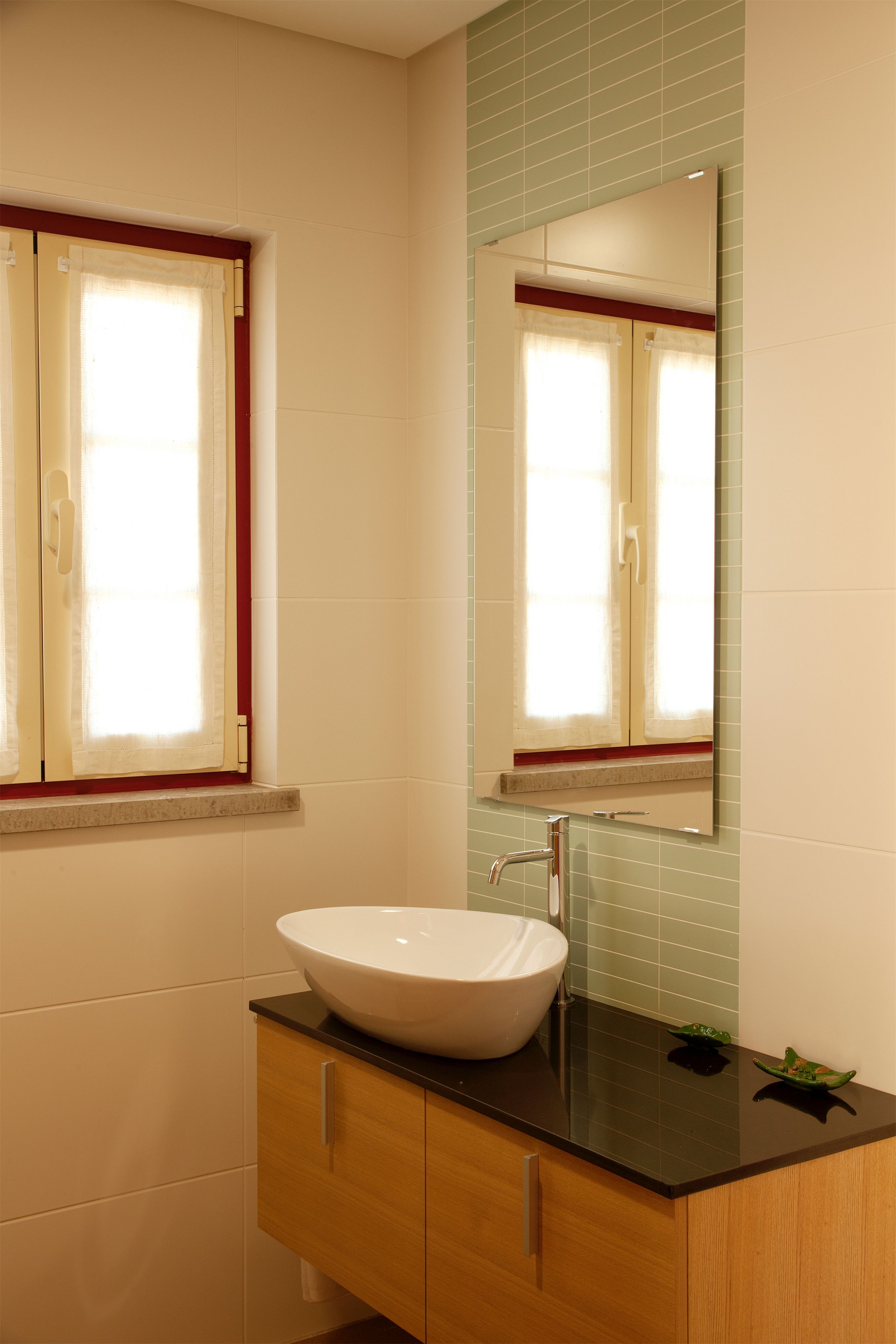 A bathroom with a white sink, wooden cabinet, and a mirror above it.