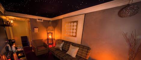 A cozy room with a sofa, a chair, a table with a lamp, and a decorative wall piece.