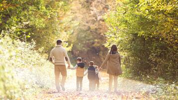 Una familia caminando por un sendero cubierto de hojas en un área boscosa.