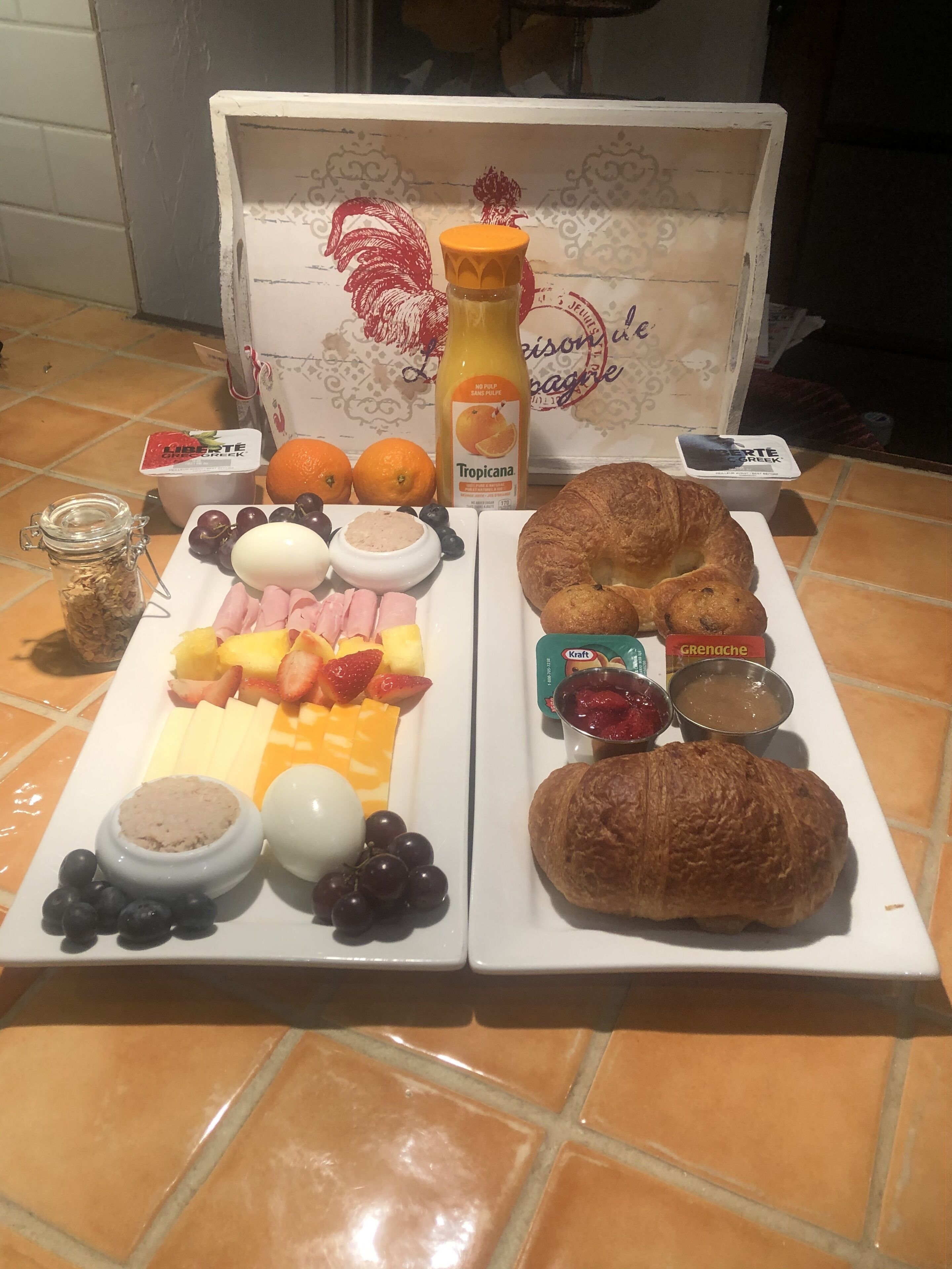 Un'abbondante colazione con frutta, formaggi e dolci su un pavimento piastrellato.