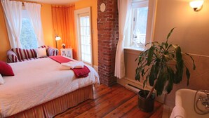 A bedroom with a large bed, a potted plant, and a bathtub. - Auberge La belle Victorienne (Magog)