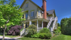 A two-story house with a front porch, a chimney, and a staircase leading to the second floor. - Auberge La belle Victorienne (Magog)
