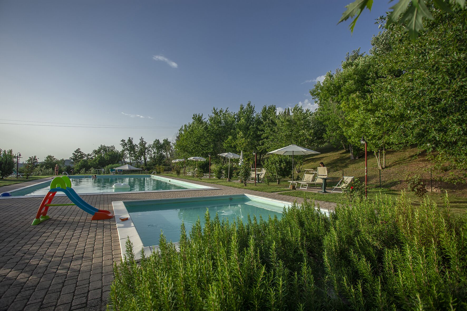 Una piscina al aire libre de temporada, sombrillas