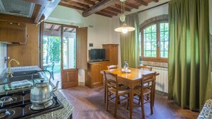 Una cocina con armarios de madera, una estufa y una mesa de comedor con sillas.