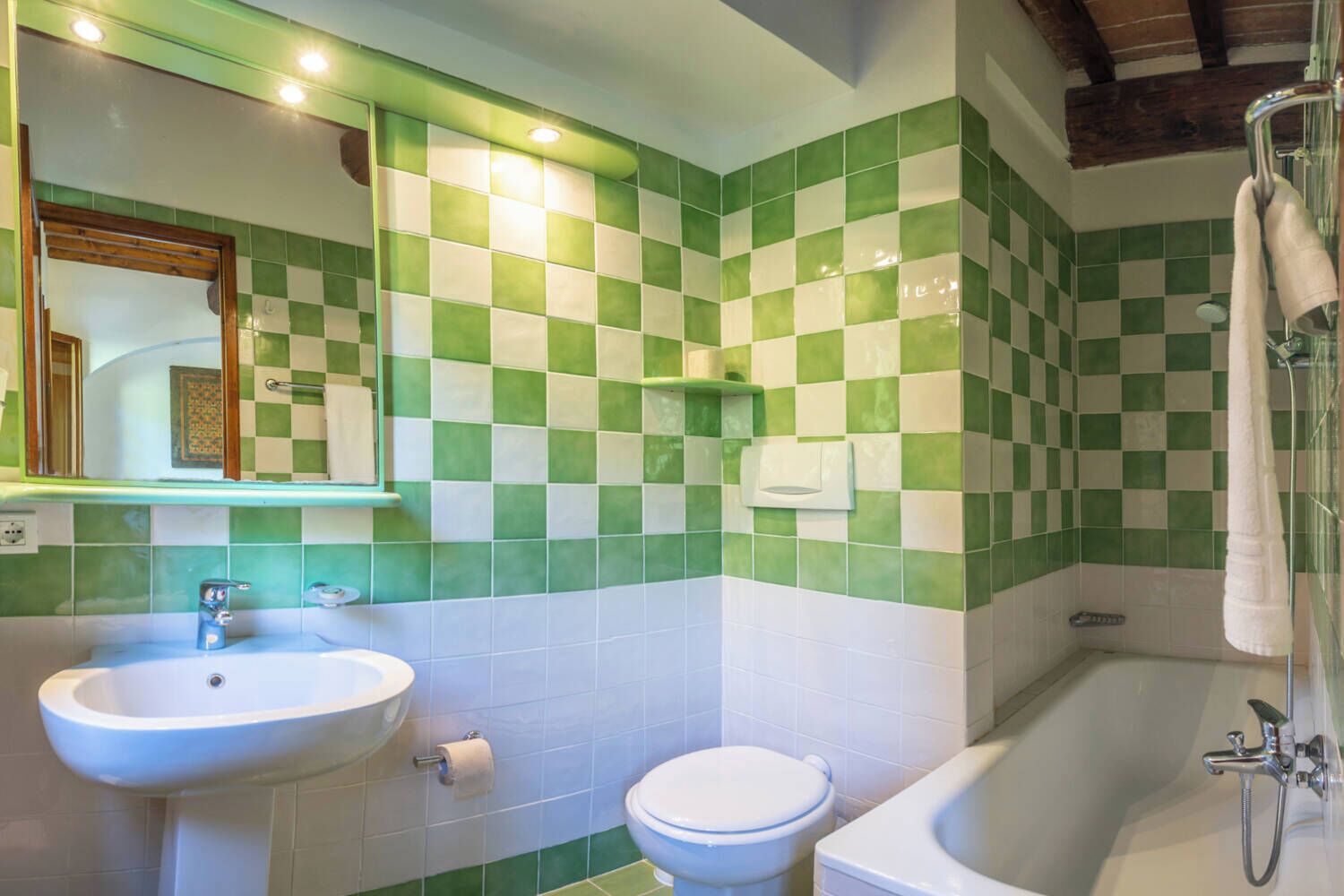 A bathroom with a sink, toilet, and bathtub, featuring green and white checkered tiles.