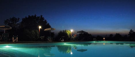 Una piscina al aire libre de temporada, sombrillas, tumbonas