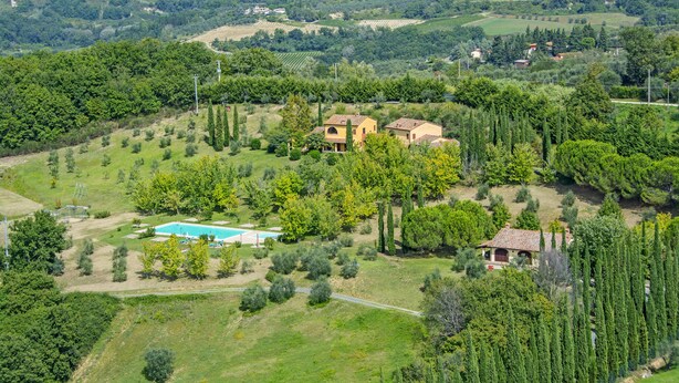 Propiedad rural con piscina, una casita y abundante vegetación.