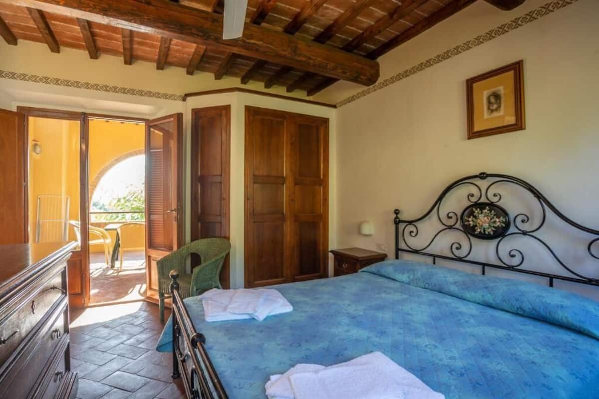 A bedroom with a bed, wooden wardrobe, and a door leading to an outdoor area.