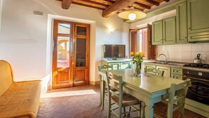 Una cocina acogedora con vigas de madera, una mesa de comedor con sillas, un televisor y una estufa.