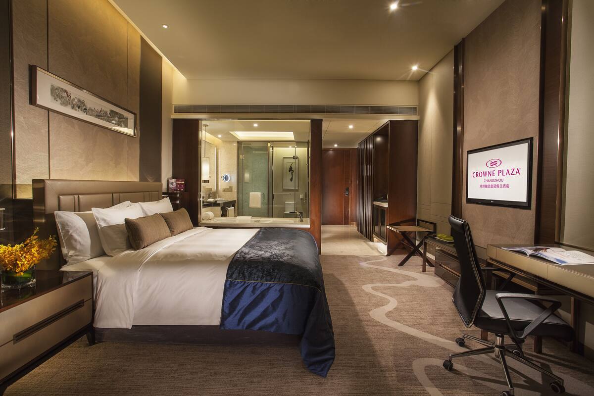 Een hotelkamer met een groot bed, een bureau en een douche.