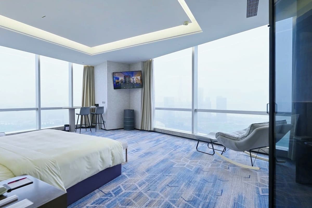 Een moderne hotelkamer met een groot bed, een bureau, een stoel, een televisie en uitzicht op de stad.