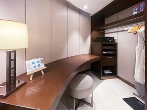 A hotel room with a wooden desk, a small easel with a sign, a chair, a coat rack with a robe, and a shelf with a microwave. - Crowne Plaza Zhangzhou by IHG (Zhangzhou)