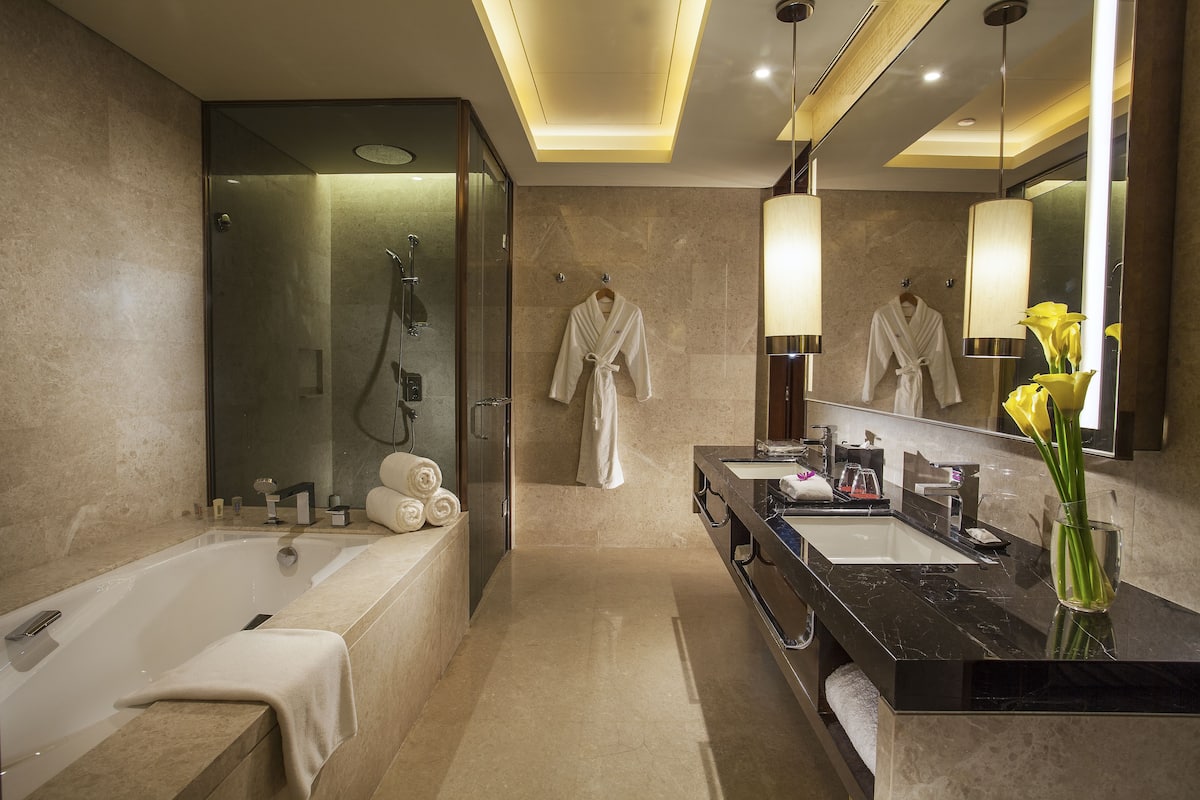 A modern bathroom with a bathtub, a large mirror, and a vanity with a sink and mirror.