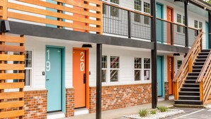 A multi-story building with numbered doors, a balcony, and a staircase. - Freebird Motor Lodge by Reverie Boutique Collection (West Yarmouth)