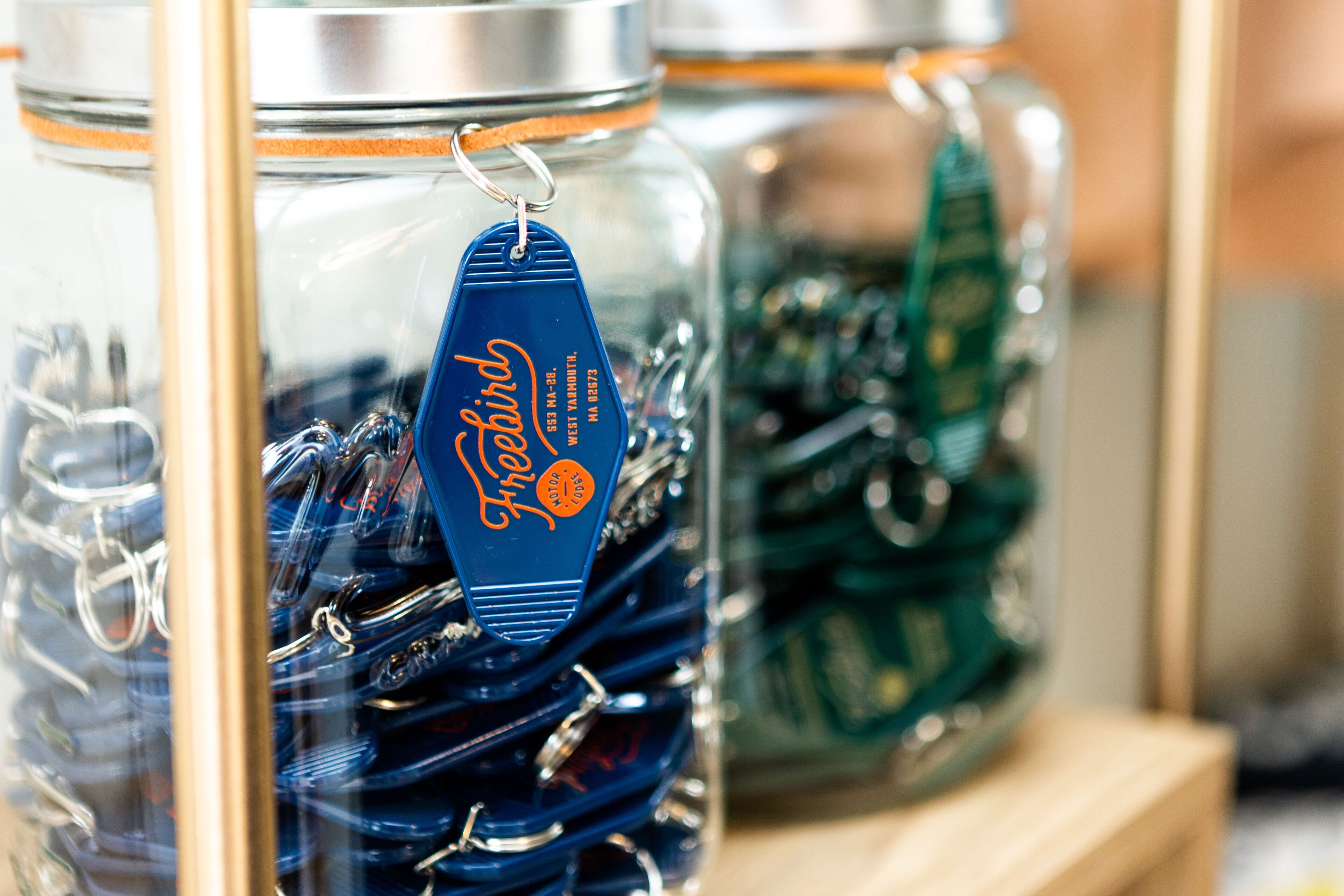 Glass jars with metal keychains and a blue tag with text.