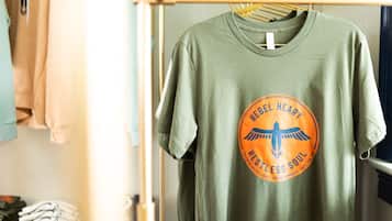 A green t-shirt with a circular logo hanging on a rack.