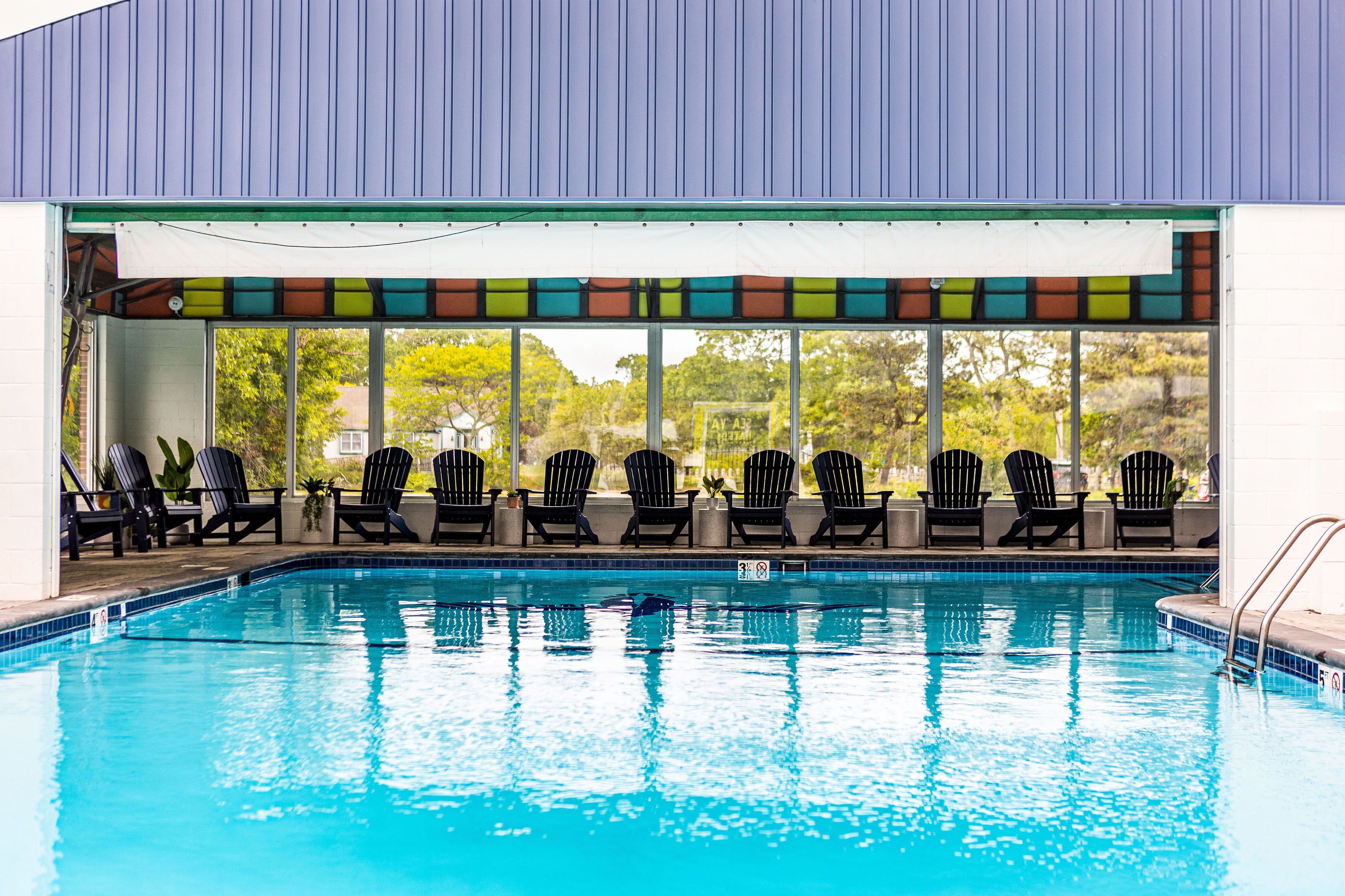 A swimming pool with black lounge chairs and a colorful awning.