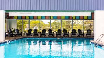 A swimming pool with black lounge chairs and a colorful awning.