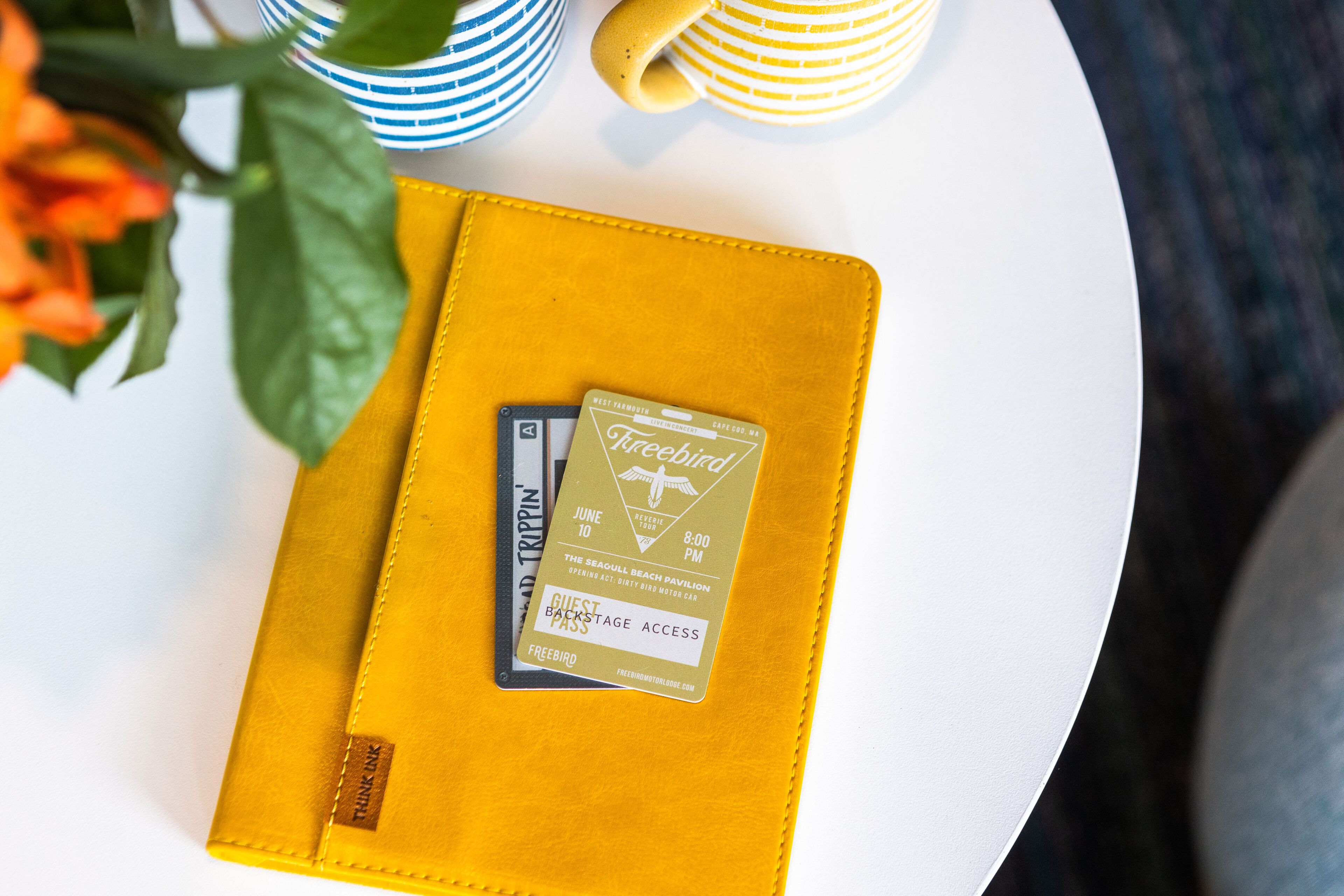 A yellow leather journal with a guest pass and a card on it.