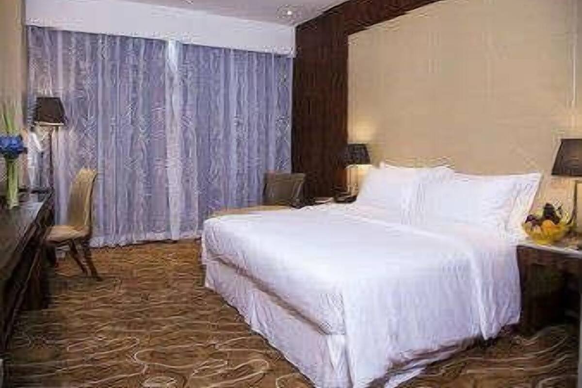 Een hotelkamer met een groot bed, een bureau met lamp en een stoel.