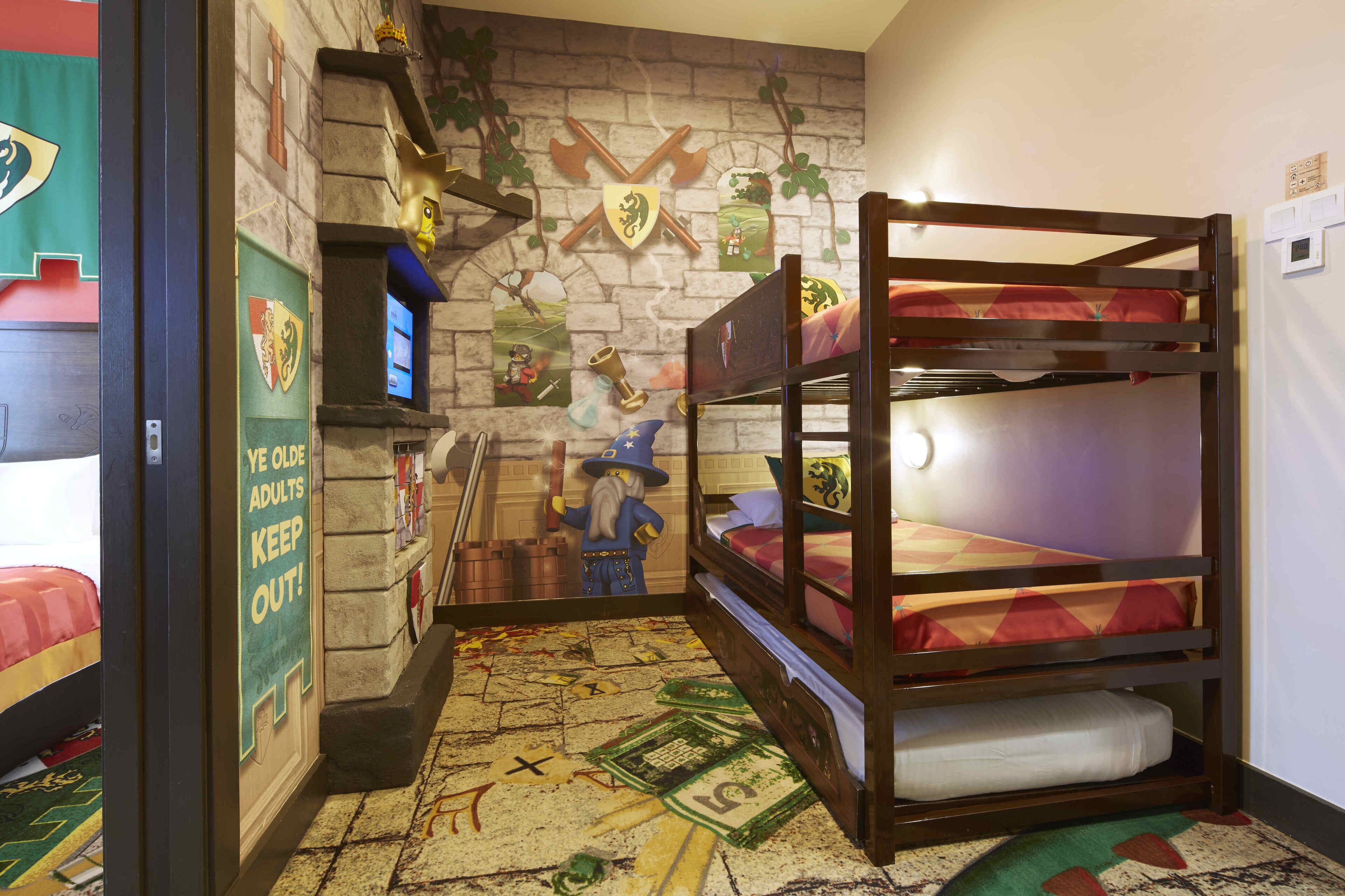 A bunk bed room with a medieval-themed wall, a small desk, and a poster on the wall.