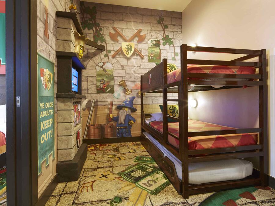 A bunk bed room with a medieval-themed wall, a small desk, and a poster on the wall.