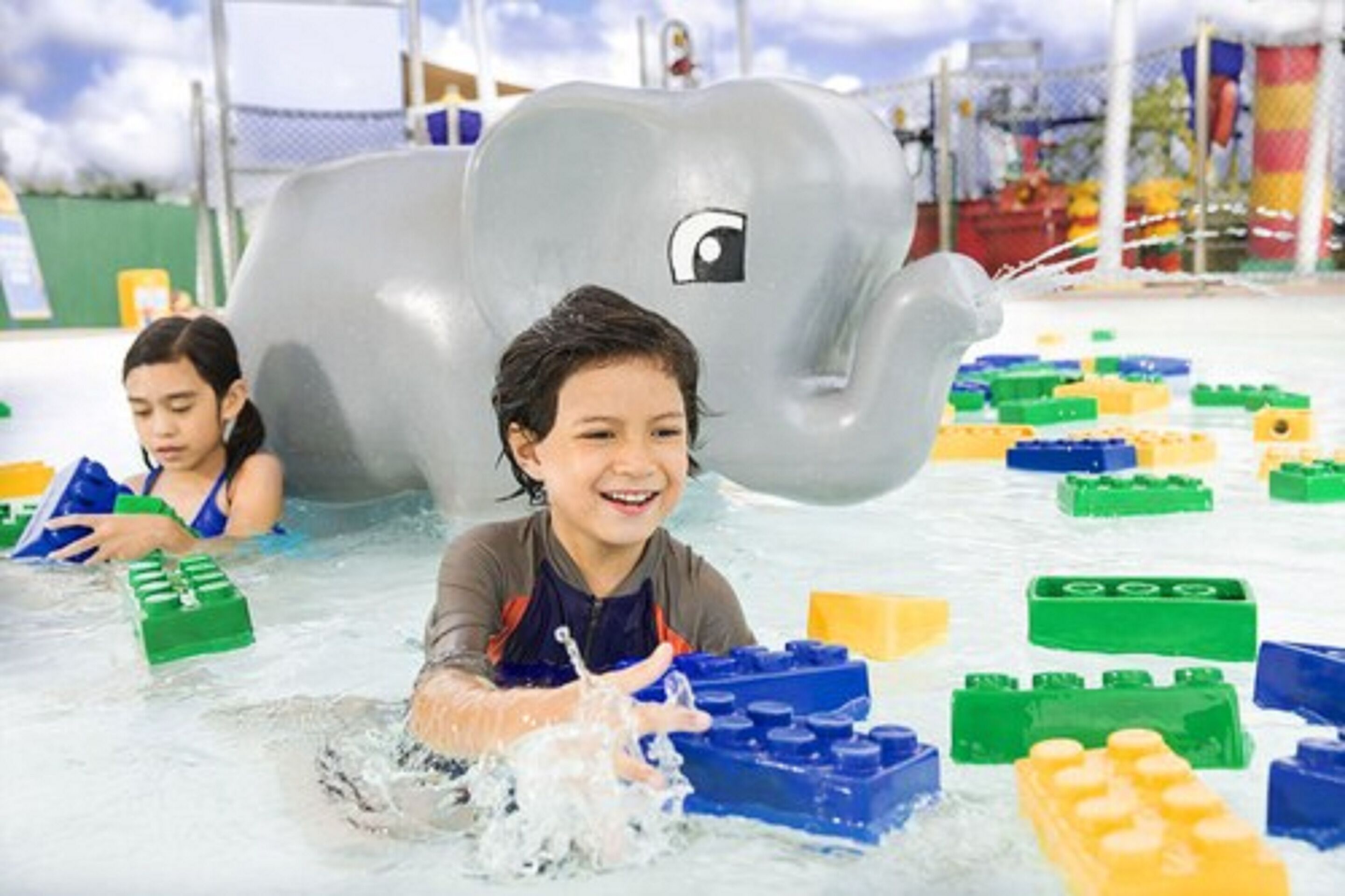 Children playing with water toys and building blocks in a water play area.