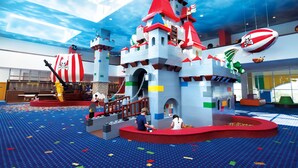 Un amplio espacio de juego interior con una estructura de castillo, toboganes y decoración temática de piratas.