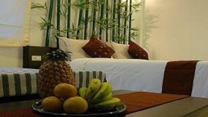 A hotel room with a bed, a bedside table with fruit, and a bamboo plant in the background. - The Dream Garden (Krabi)