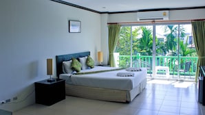 Una habitación de hotel con cama, mesita de noche, lámpara y unidad de aire acondicionado.