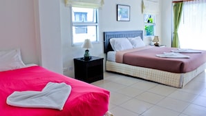 Habitación de hotel con dos camas, una mesita de noche con lámpara y una ventana con cortinas.