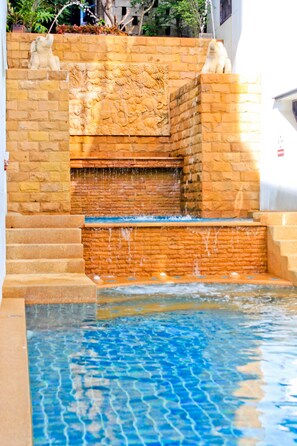 A stone water feature with a cascading waterfall and a pool at the bottom. - Ben's House (Krabi)