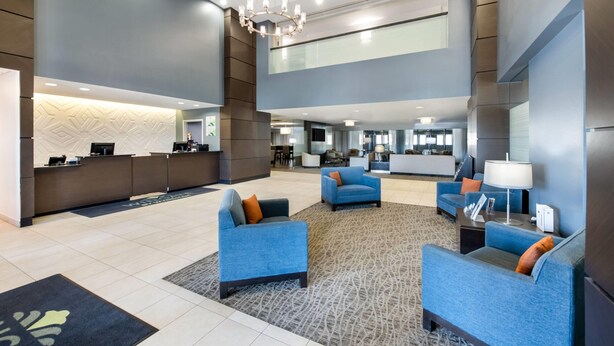 A modern lobby with a reception desk, seating area, and a chandelier. - Wingate by Wyndham Slidell/New Orleans East Area (Slidell)