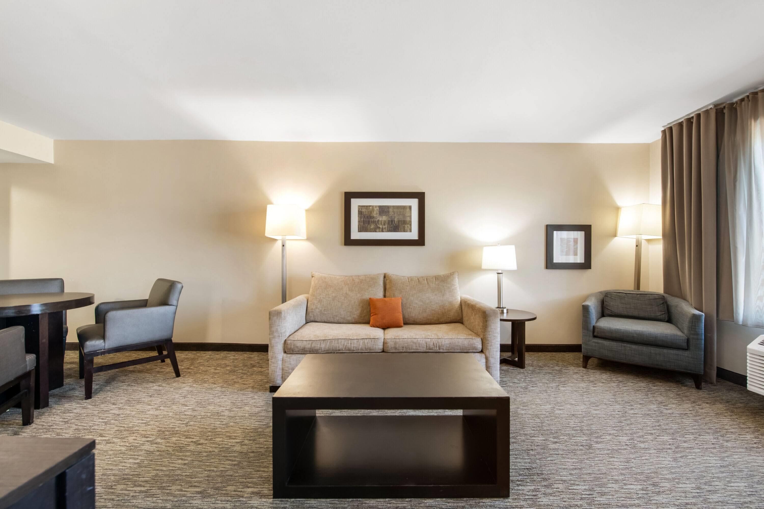 A hotel room with a sofa, two armchairs, a coffee table, and two lamps.