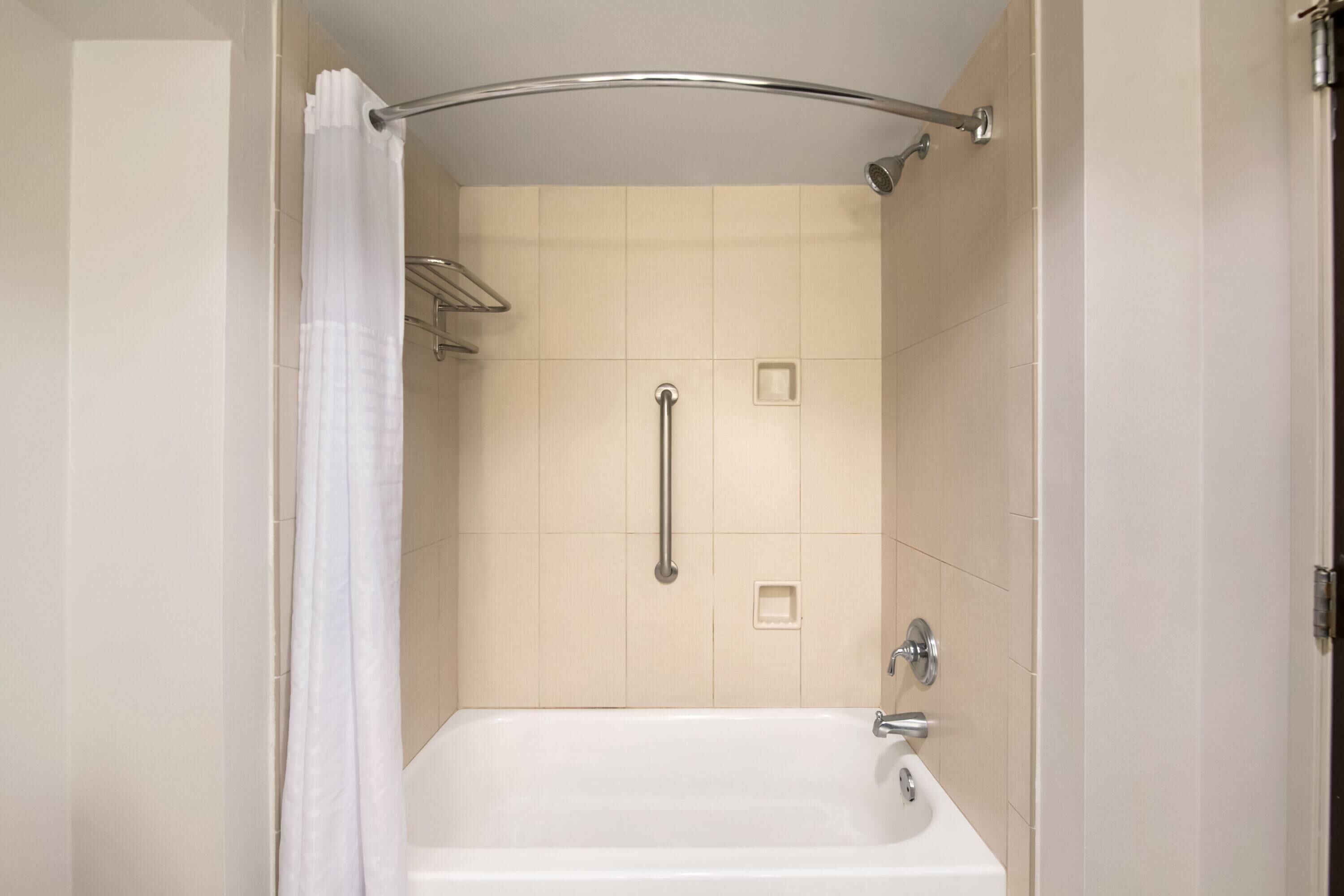 A modern bathroom with a bathtub, a shower curtain, and a grab bar.