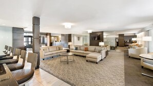 A spacious hotel lobby with a large seating area, a reception desk, and a modern interior design. - Wingate by Wyndham Slidell/New Orleans East Area (Slidell)