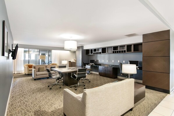 A modern hotel room with a large bed, a desk, and a seating area.