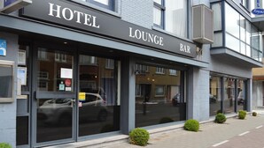 En hotelbar med loungeområde, store vinduer og moderne facade.
