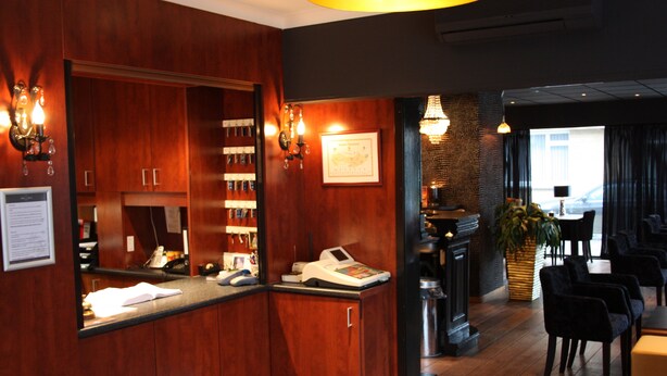En reception med træskabe, en kasseapparat og et indrammet certifikat på væggen.