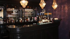 En bar med flere lysekroner, hylder med flasker og glas.