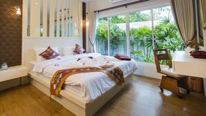 Quarto com uma cama grande, uma escrivaninha e uma janela com vista para o verde.