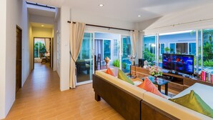 Uma sala de estar moderna com sofá, TV e vista para o exterior.