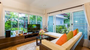 Uma sala de estar moderna com sofá, TV e mesa de centro de vidro.