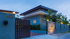 Uma casa moderna com fachada azul, portão e placa iluminada.