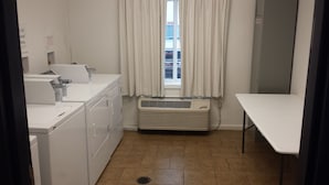 Un cuarto de lavandería con lavadora, secadora y tabla de planchar.