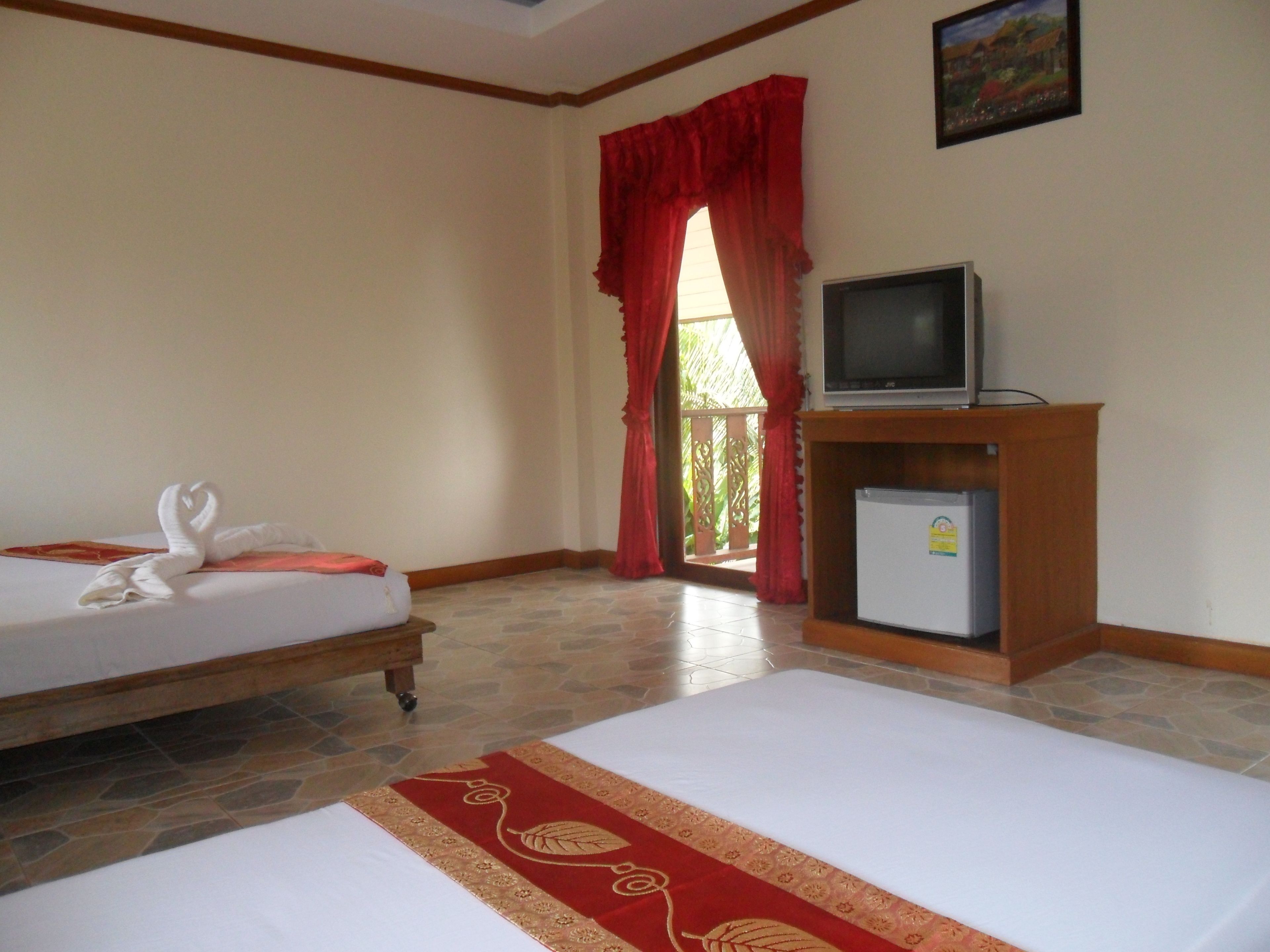 Quarto de hotel com duas camas, televisão e frigorífico.