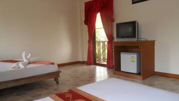 Quarto de hotel com duas camas, televisão e frigorífico.