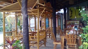 A covered outdoor seating area with wooden furniture and potted plants. - Lanta Nature House (Ko Lanta)