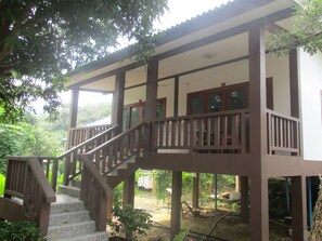 A two-story wooden house with a balcony and a staircase leading to the upper floor.